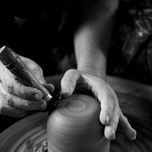 Gros plan sur des mains façonnant un vase en argile sur un tour de potier, texture de la terre humide et mouvement circulaire.