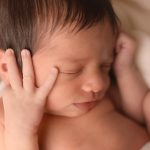 Nouveau-né endormi les mains près du visage