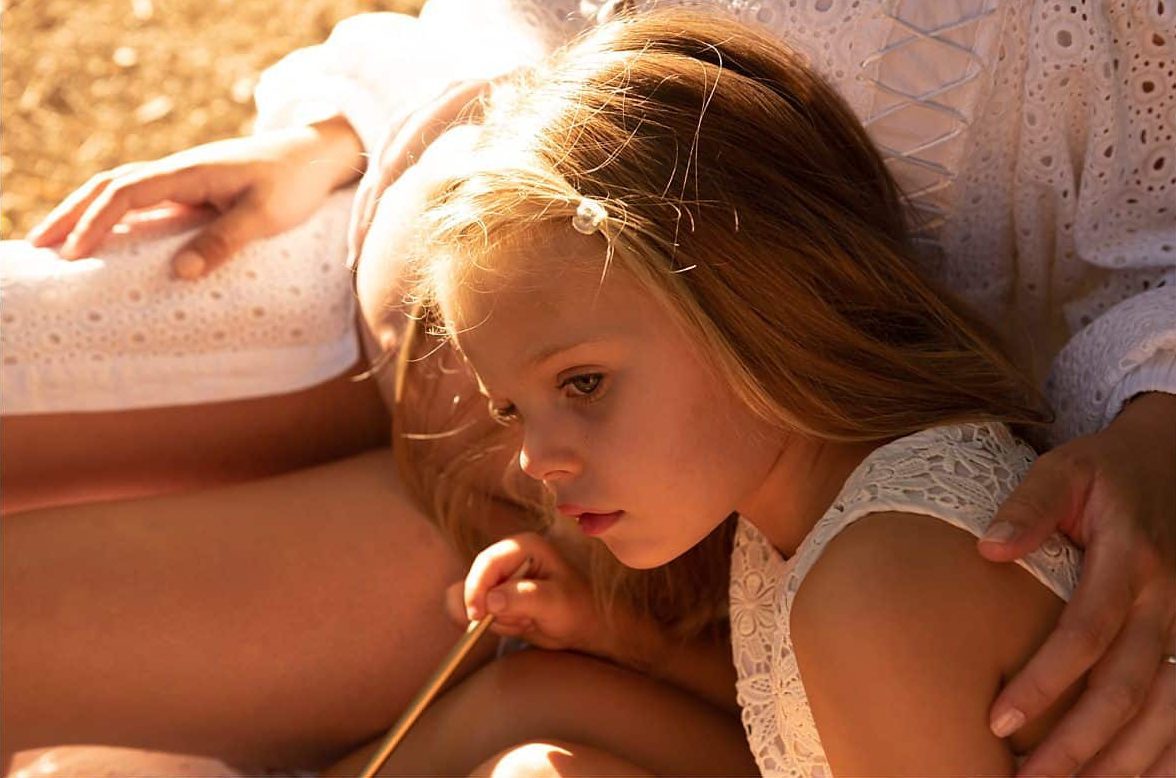 Jeune fille blonde en robe blanche regardant pensivement sur le côté, lumière dorée